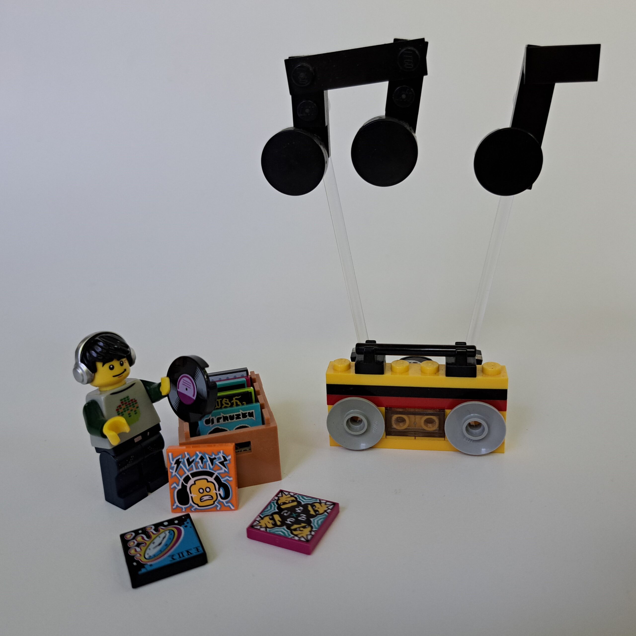 a LEGO-figure DJ, standing next to a crate of LEGO vinyl LPs; next to that a LEGO boombox pumping out LEGO tunes.