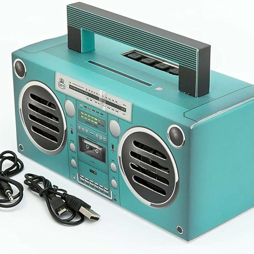 a modern turquoise boombox with cassette player and assorted cables.